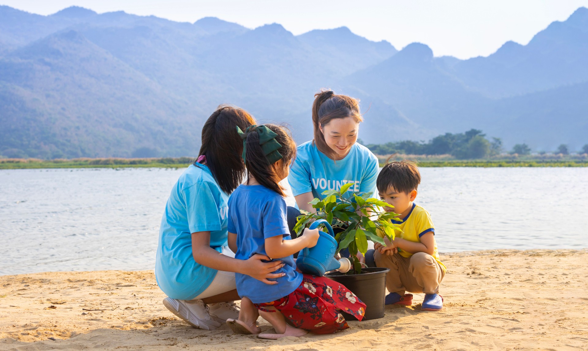 Team of volunteer worker group teaching children to planting tree in charitable social work on forest rewilding NGO work for fighting climate change and global warming in the coastline habitat concept